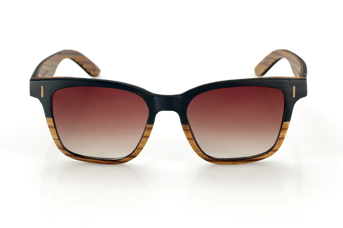 Gafas de Madera Natural de mpingo LOREA. Las gafas de sol LOREA están fabricadas en una combinación de dos maderas, Mpingo (African Black wood) en parte superior de montura y en el exterior de las varillas y Zebrano en la parte inferior de la montura y en el interior de las varillas.  Se trata de un modelo fácil de llevar sencillo y elegante con una terminación muy cuidada que te sorprenderá por su originalidad y la combinación de maderas. Medida frontal: 145x50mm Venta al Por Mayor y Detalle | Root Sunglasses® 