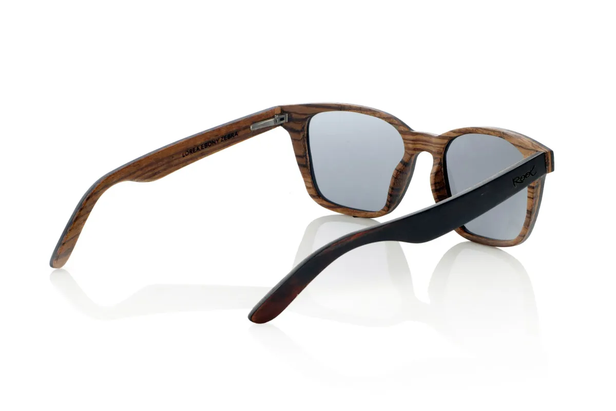 Gafas de Madera Natural de mpingo LOREA. Las gafas de sol LOREA están fabricadas en una combinación de dos maderas, Mpingo (African Black wood) en parte superior de montura y en el exterior de las varillas y Zebrano en la parte inferior de la montura y en el interior de las varillas.  Se trata de un modelo fácil de llevar sencillo y elegante con una terminación muy cuidada que te sorprenderá por su originalidad y la combinación de maderas. Medida frontal: 145x50mm Venta al Por Mayor y Detalle | Root Sunglasses® 