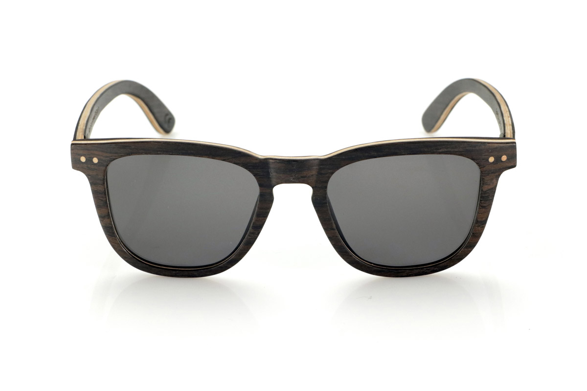 Gafas de Madera Natural de Roble ENRICO. Las gafas de sol de madera ENRICO están fabricadas con una estructura laminada de roble negro en el exterior e interior, con una fina lámina de arce natural intercalada que aporta un sutil contraste. Su diseño clásico con frontal recto y líneas definidas transmite equilibrio y solidez.

Los detalles de doble punto en el frontal resaltan su carácter artesanal, mientras que su estructura laminada proporciona resistencia sin comprometer la comodidad. Las lentes polarizadas garantizan una visión nítida, reduciendo reflejos y ofreciendo una protección total contra los rayos UV.

Un modelo atemporal que combina materiales nobles con un diseño funcional para el uso diario.

Dimensiones: 142x47mm. Calibre 49. Venta al Por Mayor y Detalle | Root Sunglasses® 