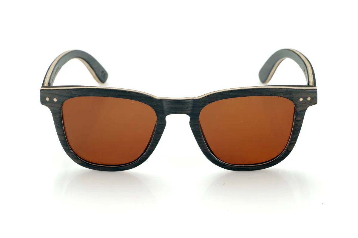 Wood eyewear of Oak ENRICO. ENRICO wooden sunglasses are made with a laminated black oak structure on the outside and inside, with a thin layer of natural maple interspersed for subtle contrast. Its classic design with a straight front and defined lines conveys balance and solidity.

Double-knit details on the front highlight its artisanal character, while its laminated structure provides strength without compromising comfort. Polarized lenses guarantee clear vision, reducing glare and offering total UV protection.

A timeless model that combines noble materials with a functional design for everyday use.

Dimensions: 142x47mm. Caliber 49. for Wholesale & Retail | Root Sunglasses® 