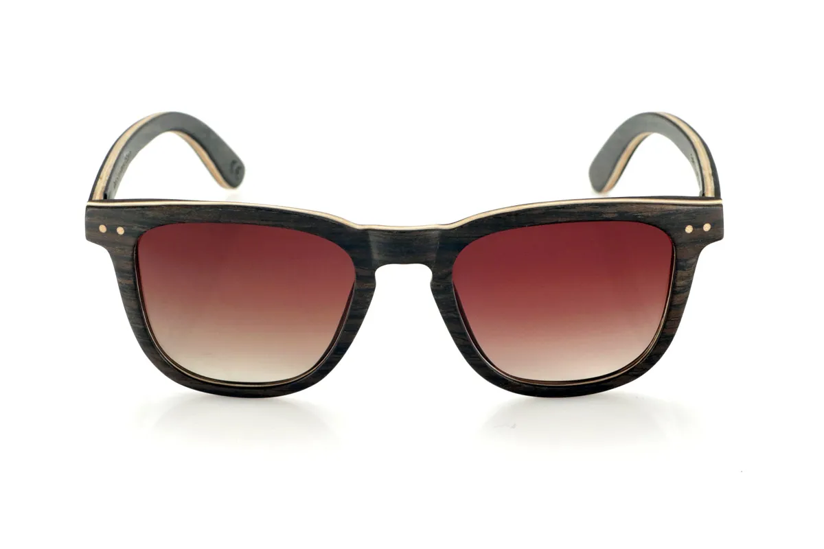 Wood eyewear of Oak ENRICO. ENRICO wooden sunglasses are made with a laminated black oak structure on the outside and inside, with a thin layer of natural maple interspersed for subtle contrast. Its classic design with a straight front and defined lines conveys balance and solidity.

Double-knit details on the front highlight its artisanal character, while its laminated structure provides strength without compromising comfort. Polarized lenses guarantee clear vision, reducing glare and offering total UV protection.

A timeless model that combines noble materials with a functional design for everyday use.

Dimensions: 142x47mm. Caliber 49. for Wholesale & Retail | Root Sunglasses® 