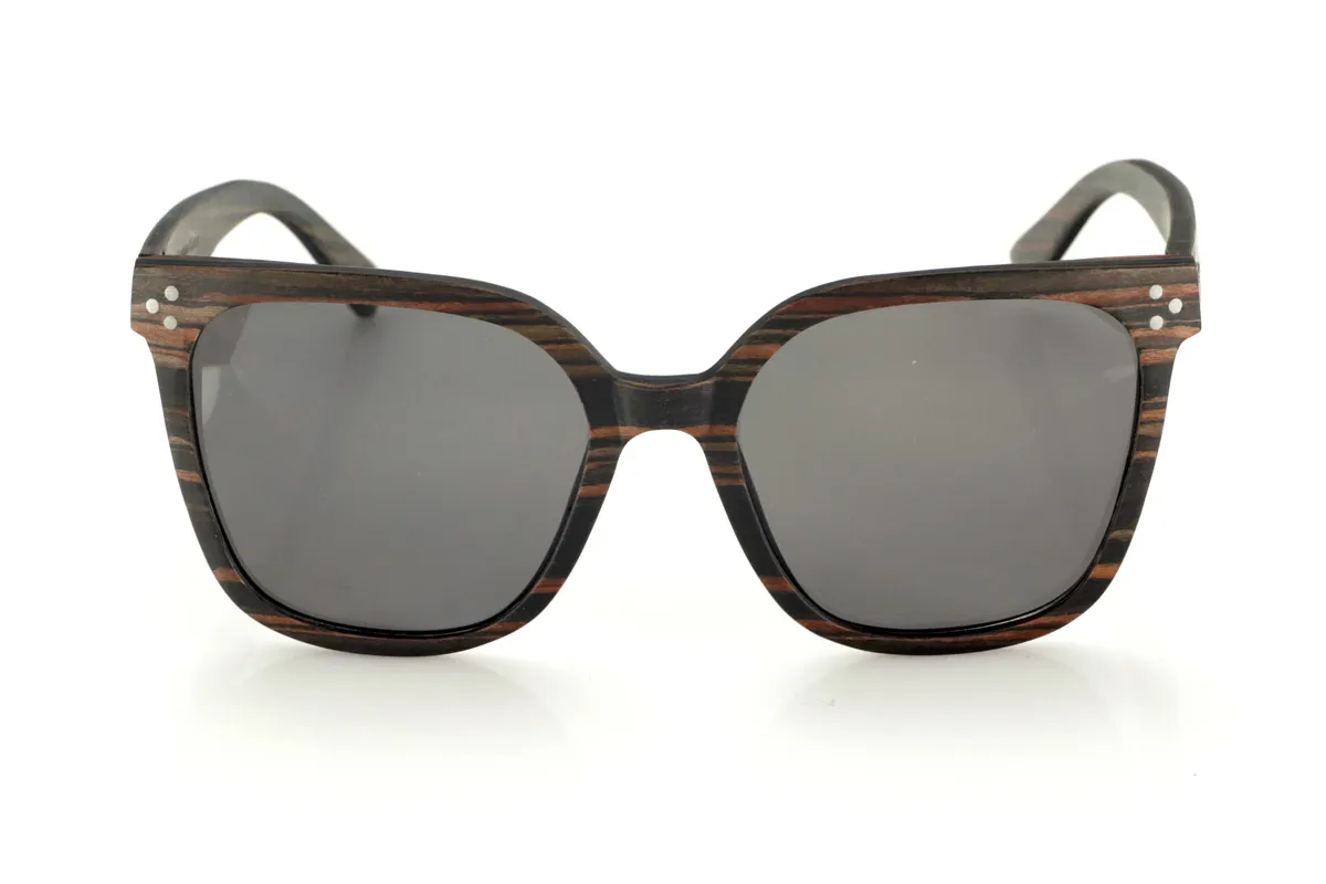Wood eyewear of Ebony OUNIZ. OUNIZ wooden sunglasses are made of ebony wood, standing out for its natural grains that add character and depth to the frame. Its wraparound square design combines elegance and functionality, offering a robust structure without compromising comfort.

Decorative details on the front reinforce its timeless aesthetic, while the laminated wood provides durability and flexibility. Polarized lenses guarantee total protection against UV rays, reducing glare and improving visual clarity.

Dimensions: 148x56mm. Caliber 56 for Wholesale & Retail | Root Sunglasses® 
