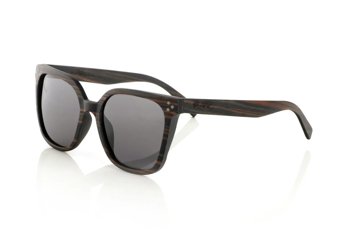 Wood eyewear of Ebony OUNIZ. OUNIZ wooden sunglasses are made of ebony wood, standing out for its natural grains that add character and depth to the frame. Its wraparound square design combines elegance and functionality, offering a robust structure without compromising comfort.

Decorative details on the front reinforce its timeless aesthetic, while the laminated wood provides durability and flexibility. Polarized lenses guarantee total protection against UV rays, reducing glare and improving visual clarity.

Dimensions: 148x56mm. Caliber 56 for Wholesale & Retail | Root Sunglasses® 
