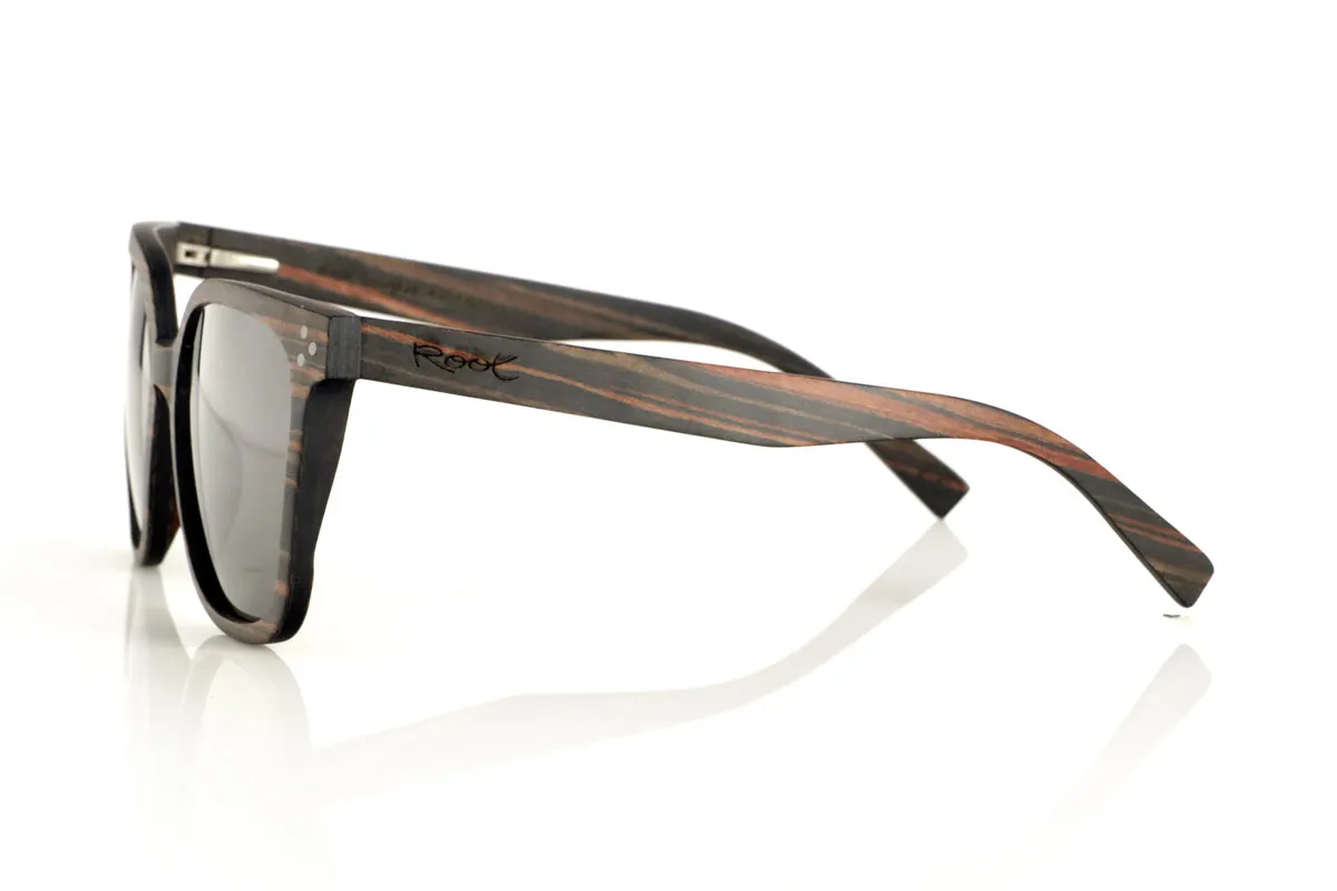Wood eyewear of Ebony OUNIZ. OUNIZ wooden sunglasses are made of ebony wood, standing out for its natural grains that add character and depth to the frame. Its wraparound square design combines elegance and functionality, offering a robust structure without compromising comfort.

Decorative details on the front reinforce its timeless aesthetic, while the laminated wood provides durability and flexibility. Polarized lenses guarantee total protection against UV rays, reducing glare and improving visual clarity.

Dimensions: 148x56mm. Caliber 56 for Wholesale & Retail | Root Sunglasses® 