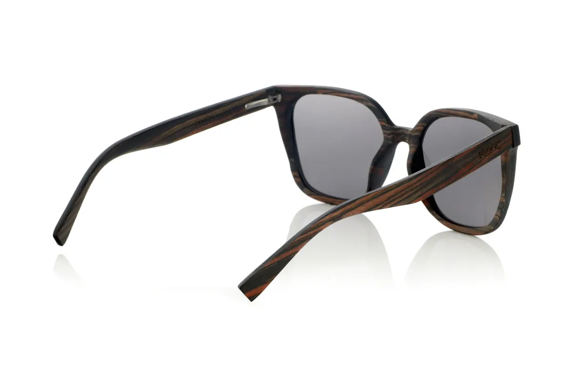 Wood eyewear of Ebony OUNIZ. OUNIZ wooden sunglasses are made of ebony wood, standing out for its natural grains that add character and depth to the frame. Its wraparound square design combines elegance and functionality, offering a robust structure without compromising comfort.

Decorative details on the front reinforce its timeless aesthetic, while the laminated wood provides durability and flexibility. Polarized lenses guarantee total protection against UV rays, reducing glare and improving visual clarity.

Dimensions: 148x56mm. Caliber 56 for Wholesale & Retail | Root Sunglasses® 