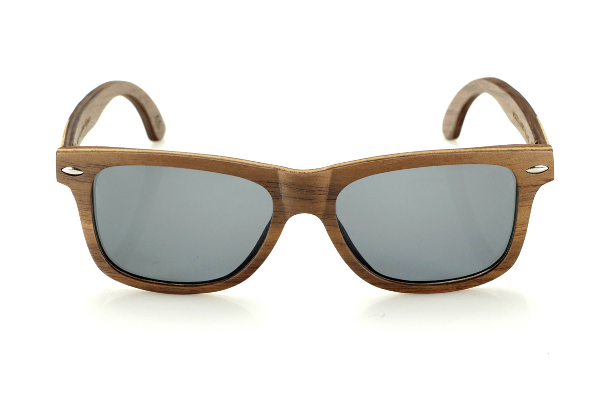Gafas de Madera Natural de Walnut WOODSUNSET SK. Las gafas de sol de madera modelo Woodsunset están elaboradas en madera de nogal negro, ofreciendo un diseño elegante y atemporal con un acabado natural. Su estructura laminada incluye una lámina intercalada de arce natural, proporcionando un sutil contraste que realza su sofisticación.

Las patillas presentan un detalle único con una combinación de nogal y roble, aportando un toque distintivo a este modelo. Además, el frontal cuenta con pequeños adornos metálicos, que no solo refuerzan la estructura, sino que también aportan un aire vintage a su diseño.

Gracias a su forma clásica y versátil, las Woodsunset son una excelente opción tanto para hombres como para mujeres que buscan unas gafas de madera con carácter y estilo.

Medidas: 147x47 Calibre: 49 Venta al Por Mayor y Detalle | Root Sunglasses® 