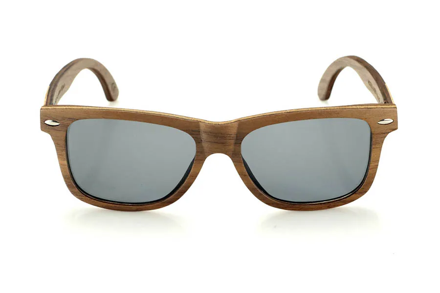 Gafas de Madera Natural de Walnut WOODSUNSET SK. Las gafas de sol de madera modelo Woodsunset están elaboradas en madera de nogal negro, ofreciendo un diseño elegante y atemporal con un acabado natural. Su estructura laminada incluye una lámina intercalada de arce natural, proporcionando un sutil contraste que realza su sofisticación.

Las patillas presentan un detalle único con una combinación de nogal y roble, aportando un toque distintivo a este modelo. Además, el frontal cuenta con pequeños adornos metálicos, que no solo refuerzan la estructura, sino que también aportan un aire vintage a su diseño.

Gracias a su forma clásica y versátil, las Woodsunset son una excelente opción tanto para hombres como para mujeres que buscan unas gafas de madera con carácter y estilo.

Medidas: 147x47 Calibre: 49 Venta al Por Mayor y Detalle | Root Sunglasses® 