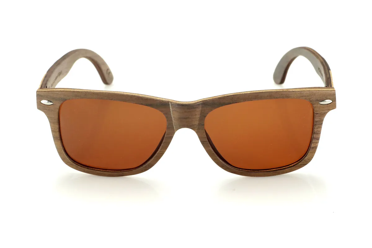 Gafas de Madera Natural de Walnut WOODSUNSET SK. Las gafas de sol de madera modelo Woodsunset están elaboradas en madera de nogal negro, ofreciendo un diseño elegante y atemporal con un acabado natural. Su estructura laminada incluye una lámina intercalada de arce natural, proporcionando un sutil contraste que realza su sofisticación.

Las patillas presentan un detalle único con una combinación de nogal y roble, aportando un toque distintivo a este modelo. Además, el frontal cuenta con pequeños adornos metálicos, que no solo refuerzan la estructura, sino que también aportan un aire vintage a su diseño.

Gracias a su forma clásica y versátil, las Woodsunset son una excelente opción tanto para hombres como para mujeres que buscan unas gafas de madera con carácter y estilo.

Medidas: 147x47 Calibre: 49 Venta al Por Mayor y Detalle | Root Sunglasses® 