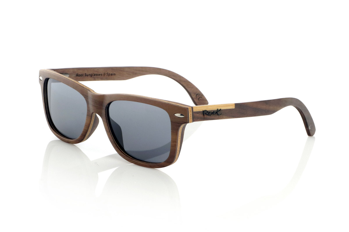 Gafas de Madera Natural de Walnut WOODSUNSET SK. Las gafas de sol de madera modelo Woodsunset están elaboradas en madera de nogal negro, ofreciendo un diseño elegante y atemporal con un acabado natural. Su estructura laminada incluye una lámina intercalada de arce natural, proporcionando un sutil contraste que realza su sofisticación.

Las patillas presentan un detalle único con una combinación de nogal y roble, aportando un toque distintivo a este modelo. Además, el frontal cuenta con pequeños adornos metálicos, que no solo refuerzan la estructura, sino que también aportan un aire vintage a su diseño.

Gracias a su forma clásica y versátil, las Woodsunset son una excelente opción tanto para hombres como para mujeres que buscan unas gafas de madera con carácter y estilo.

Medidas: 147x47 Calibre: 49 Venta al Por Mayor y Detalle | Root Sunglasses® 