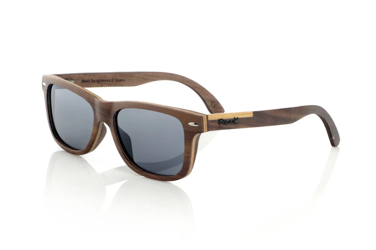 Gafas de Madera Natural de Walnut WOODSUNSET SK. Las gafas de sol de madera modelo Woodsunset están elaboradas en madera de nogal negro, ofreciendo un diseño elegante y atemporal con un acabado natural. Su estructura laminada incluye una lámina intercalada de arce natural, proporcionando un sutil contraste que realza su sofisticación.

Las patillas presentan un detalle único con una combinación de nogal y roble, aportando un toque distintivo a este modelo. Además, el frontal cuenta con pequeños adornos metálicos, que no solo refuerzan la estructura, sino que también aportan un aire vintage a su diseño.

Gracias a su forma clásica y versátil, las Woodsunset son una excelente opción tanto para hombres como para mujeres que buscan unas gafas de madera con carácter y estilo.

Medidas: 147x47 Calibre: 49 Venta al Por Mayor y Detalle | Root Sunglasses® 