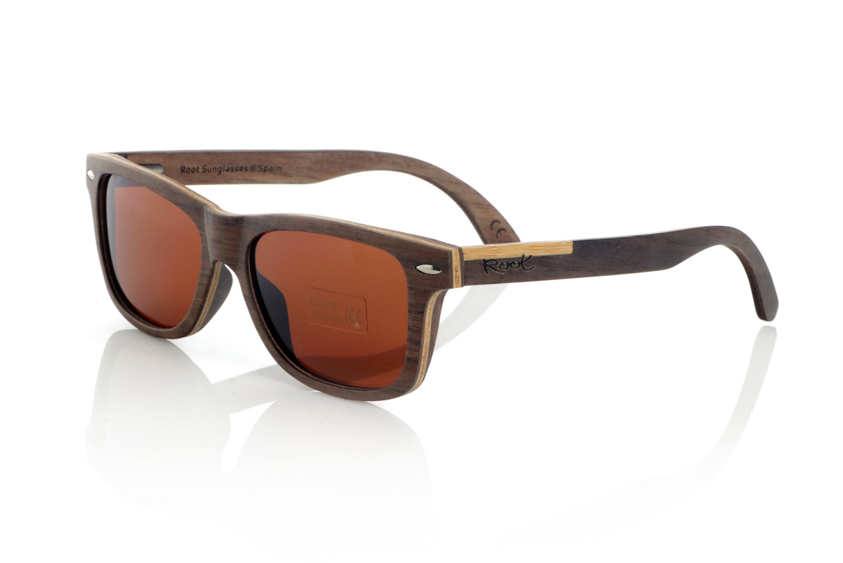 Gafas de Madera Natural de Walnut WOODSUNSET SK. Las gafas de sol de madera modelo Woodsunset están elaboradas en madera de nogal negro, ofreciendo un diseño elegante y atemporal con un acabado natural. Su estructura laminada incluye una lámina intercalada de arce natural, proporcionando un sutil contraste que realza su sofisticación.

Las patillas presentan un detalle único con una combinación de nogal y roble, aportando un toque distintivo a este modelo. Además, el frontal cuenta con pequeños adornos metálicos, que no solo refuerzan la estructura, sino que también aportan un aire vintage a su diseño.

Gracias a su forma clásica y versátil, las Woodsunset son una excelente opción tanto para hombres como para mujeres que buscan unas gafas de madera con carácter y estilo.

Medidas: 147x47 Calibre: 49 Venta al Por Mayor y Detalle | Root Sunglasses® 