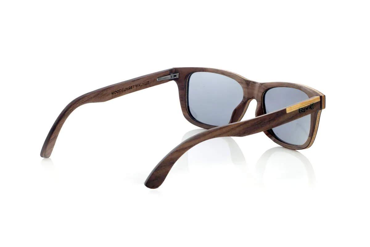 Gafas de Madera Natural de Walnut WOODSUNSET SK. Las gafas de sol de madera modelo Woodsunset están elaboradas en madera de nogal negro, ofreciendo un diseño elegante y atemporal con un acabado natural. Su estructura laminada incluye una lámina intercalada de arce natural, proporcionando un sutil contraste que realza su sofisticación.

Las patillas presentan un detalle único con una combinación de nogal y roble, aportando un toque distintivo a este modelo. Además, el frontal cuenta con pequeños adornos metálicos, que no solo refuerzan la estructura, sino que también aportan un aire vintage a su diseño.

Gracias a su forma clásica y versátil, las Woodsunset son una excelente opción tanto para hombres como para mujeres que buscan unas gafas de madera con carácter y estilo.

Medidas: 147x47 Calibre: 49 Venta al Por Mayor y Detalle | Root Sunglasses® 