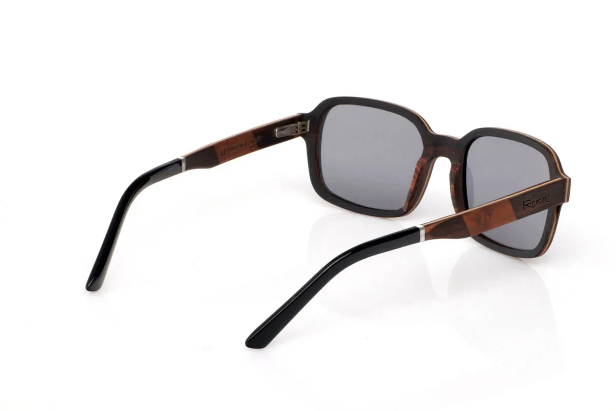 Gafas de Madera Natural de Ébano LENNY. Las gafas de madera LENNY tienen una presencia que se siente firme pero sin imponerse. El frontal combina la profundidad del ébano con la calidez del roble y nogal, creando un contraste marcado pero equilibrado. La forma, de líneas rectas suavizadas, aporta carácter y encaja con naturalidad en un estilo cotidiano con personalidad.

La mezcla de maderas en las varillas añade riqueza visual y textura, con vetas visibles que hacen que cada gafa sea diferente. Se sienten sólidas pero ligeras, cómodas desde el primer momento. De esas piezas que no necesitan exagerar para transmitir seguridad, calma y autenticidad.

Protección completa frente a los rayos UV.

Medidas: 142x48
Calibre: 52 Venta al Por Mayor y Detalle | Root Sunglasses® 