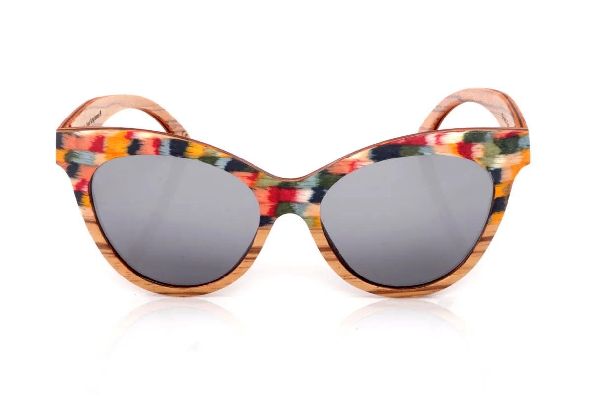 Gafas de Madera Natural de Zebrano GHANA. Las gafas de madera GHANA destacan por una energía diferente, más atrevida, más viva. El frontal mezcla la veta natural del zebrano con un patrón multicolor que rompe con lo esperado, creando una pieza única que no pasa desapercibida. La forma, ligeramente cat-eye y envolvente, aporta personalidad sin perder equilibrio.

Las varillas mantienen la esencia natural de la madera, con vetas marcadas que contrastan con el juego de colores del frontal. El resultado es ligero, cómodo y muy expresivo. Un modelo para quienes no buscan encajar, sino mostrar su forma de ver el mundo con autenticidad.

Protección completa frente a los rayos UV.

Medidas: 148x53
Calibre: 54 Venta al Por Mayor y Detalle | Root Sunglasses® 