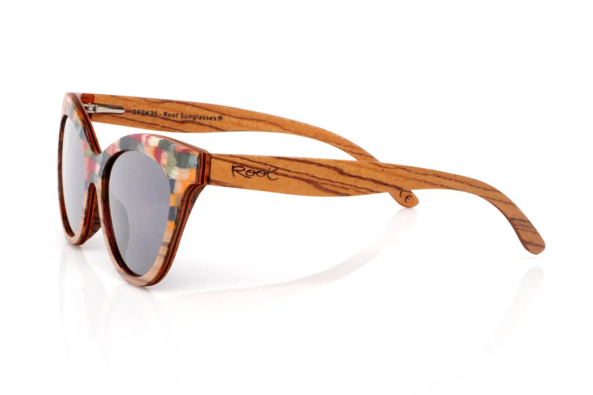 Gafas de Madera Natural de Zebrano GHANA. Las gafas de madera GHANA destacan por una energía diferente, más atrevida, más viva. El frontal mezcla la veta natural del zebrano con un patrón multicolor que rompe con lo esperado, creando una pieza única que no pasa desapercibida. La forma, ligeramente cat-eye y envolvente, aporta personalidad sin perder equilibrio.

Las varillas mantienen la esencia natural de la madera, con vetas marcadas que contrastan con el juego de colores del frontal. El resultado es ligero, cómodo y muy expresivo. Un modelo para quienes no buscan encajar, sino mostrar su forma de ver el mundo con autenticidad.

Protección completa frente a los rayos UV.

Medidas: 148x53
Calibre: 54 Venta al Por Mayor y Detalle | Root Sunglasses® 