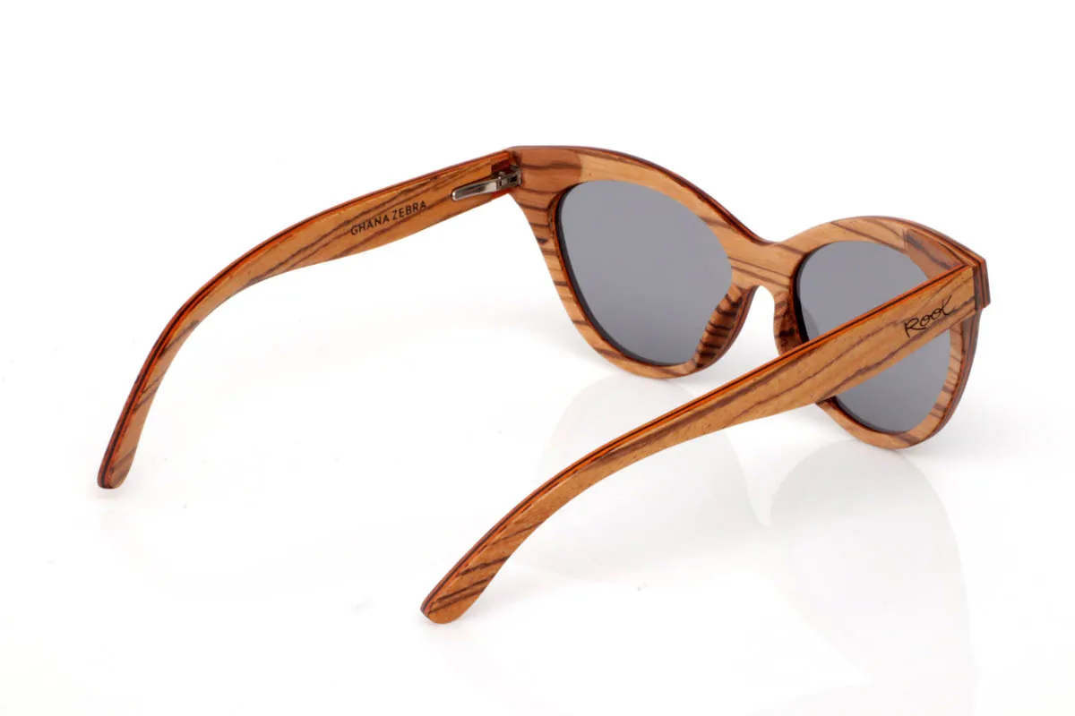 Gafas de Madera Natural de Zebrano GHANA. Las gafas de madera GHANA destacan por una energía diferente, más atrevida, más viva. El frontal mezcla la veta natural del zebrano con un patrón multicolor que rompe con lo esperado, creando una pieza única que no pasa desapercibida. La forma, ligeramente cat-eye y envolvente, aporta personalidad sin perder equilibrio.

Las varillas mantienen la esencia natural de la madera, con vetas marcadas que contrastan con el juego de colores del frontal. El resultado es ligero, cómodo y muy expresivo. Un modelo para quienes no buscan encajar, sino mostrar su forma de ver el mundo con autenticidad.

Protección completa frente a los rayos UV.

Medidas: 148x53
Calibre: 54 Venta al Por Mayor y Detalle | Root Sunglasses® 