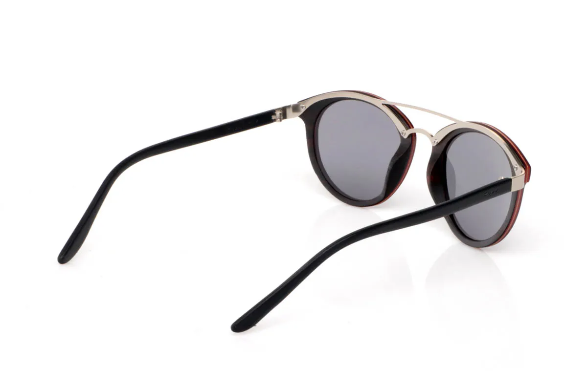 Gafas de Madera Natural de Ébano IQUAD. Las gafas de madera IQUAD destacan por su equilibrio entre sofisticación y sencillez. El frontal en ébano, con su tono oscuro profundo y vetas sutiles, transmite una elegancia natural que no necesita excesos. La doble barra metálica aporta un aire contemporáneo y ligero, creando un contraste limpio y muy actual.

La forma redondeada suaviza el conjunto, haciéndolas fáciles de llevar en cualquier situación. Las varillas, finas y ligeras, refuerzan esa sensación de comodidad y ligereza, acompañando sin esfuerzo. Son gafas de madera pensadas para quienes valoran los detalles y buscan un estilo discreto pero con personalidad.

Protección completa frente a los rayos UV.

Medidas: 138x50
Calibre: 48 Venta al Por Mayor y Detalle | Root Sunglasses® 