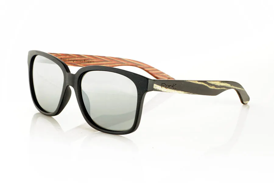 Wood eyewear of Zebrano PABLO. PABLO Sunglasses with laminated black Zebrawood (Black Ice Tree) temples with its characteristic light grain, and a multicolored skateboard-style interior. The matte black front adds a sober touch that contrasts with the vibrant interior, resulting in a modern and original design. Lightweight and comfortable for everyday wear, with polarized lenses and UV protection for greater comfort and visual safety. Measurements: 143 x 50 mm. Caliber 55. for Wholesale & Retail | Root Sunglasses® 