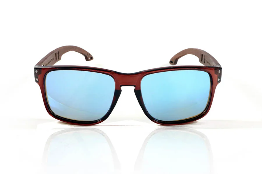 Wood eyewear of Walnut SHANN. SHANN Sunglasses with solid walnut wood temples and spring-free hardware, featuring a decorative metal detail on the exterior. The transparent brown front with a glossy finish features two metal dots on each side, reinforcing its modern and distinctive style. A sturdy, comfortable, and distinctive model, equipped with blue mirror polarized lenses and UV protection. Measurements: 146 x 48 mm. Caliber 55. for Wholesale & Retail | Root Sunglasses® 