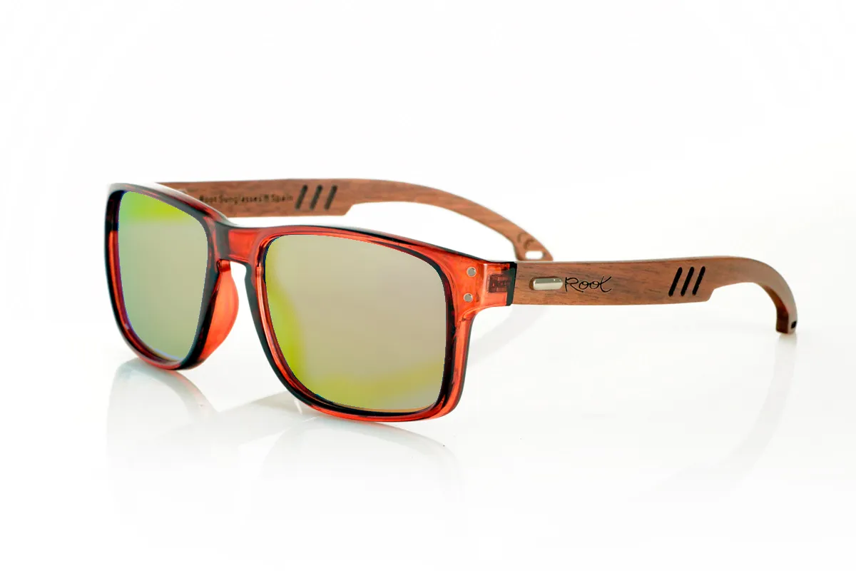 Wood eyewear of Walnut SHANN. SHANN Sunglasses with solid walnut wood temples and spring-free hardware, featuring a decorative metal detail on the exterior. The transparent brown front with a glossy finish features two metal dots on each side, reinforcing its modern and distinctive style. A sturdy, comfortable, and distinctive model, equipped with blue mirror polarized lenses and UV protection. Measurements: 146 x 48 mm. Caliber 55. for Wholesale & Retail | Root Sunglasses® 