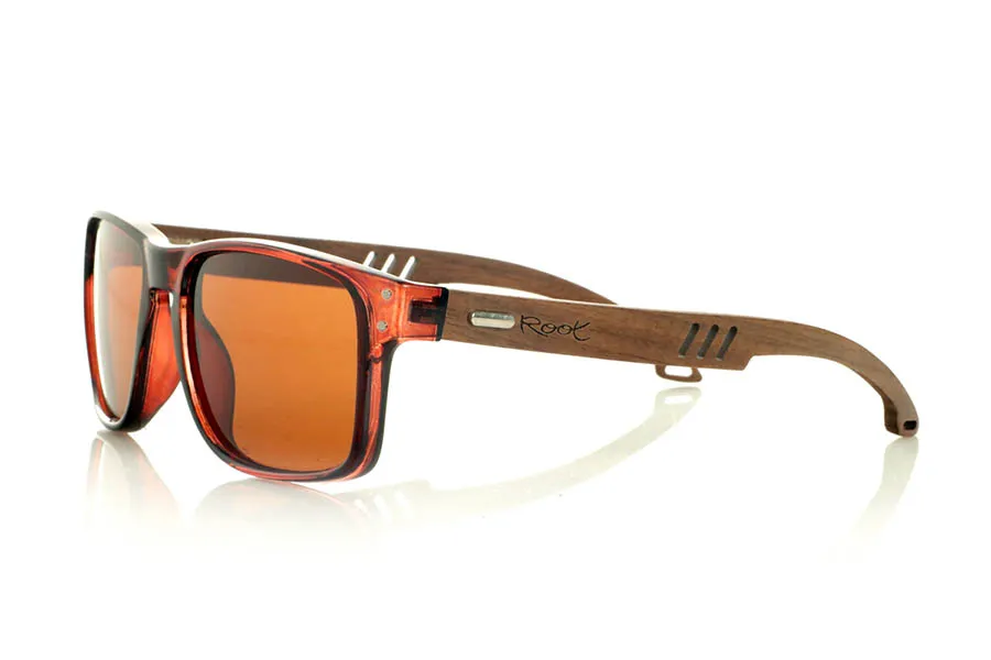 Wood eyewear of Walnut SHANN. SHANN Sunglasses with solid walnut wood temples and spring-free hardware, featuring a decorative metal detail on the exterior. The transparent brown front with a glossy finish features two metal dots on each side, reinforcing its modern and distinctive style. A sturdy, comfortable, and distinctive model, equipped with blue mirror polarized lenses and UV protection. Measurements: 146 x 48 mm. Caliber 55. for Wholesale & Retail | Root Sunglasses® 