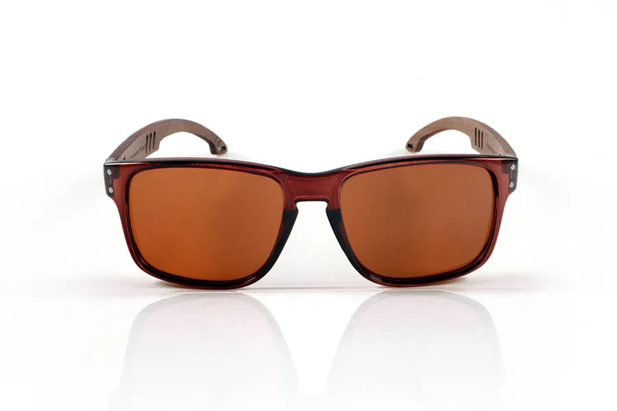 Wood eyewear of Walnut SHANN. SHANN Sunglasses with solid walnut wood temples and spring-free hardware, featuring a decorative metal detail on the exterior. The transparent brown front with a glossy finish features two metal dots on each side, reinforcing its modern and distinctive style. A sturdy, comfortable, and distinctive model, equipped with blue mirror polarized lenses and UV protection. Measurements: 146 x 48 mm. Caliber 55. for Wholesale & Retail | Root Sunglasses® 