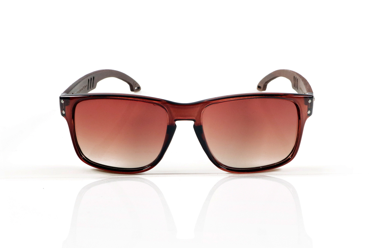 Wood eyewear of Walnut SHANN. SHANN Sunglasses with solid walnut wood temples and spring-free hardware, featuring a decorative metal detail on the exterior. The transparent brown front with a glossy finish features two metal dots on each side, reinforcing its modern and distinctive style. A sturdy, comfortable, and distinctive model, equipped with blue mirror polarized lenses and UV protection. Measurements: 146 x 48 mm. Caliber 55. for Wholesale & Retail | Root Sunglasses® 