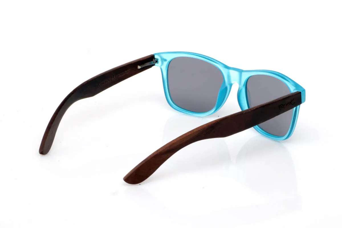 Gafas de Madera Natural de Walnut SUN BLUE ST. Las gafas de madera SUN BLUE ST transmiten frescura desde el primer vistazo. Un frontal limpio y ligero, con montura transparente mate en tono azul que suaviza la luz y aporta un efecto sutil y equilibrado. Una forma pensada para el día a día, fácil de llevar y sin complicaciones.

Las varillas de madera de nogal aportan ese contraste natural que define el modelo, con veta visible y un tacto cálido que conecta con lo auténtico. Son cómodas, ligeras y con una energía suave que acompaña sin imponerse. De esas gafas que encajan contigo sin esfuerzo.

Protección completa frente a los rayos UV.

Medidas: 148x49
Calibre: 54 Venta al Por Mayor y Detalle | Root Sunglasses® 