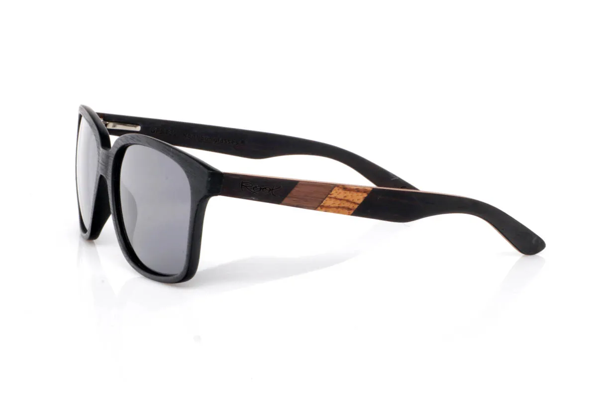 Gafas de Madera Natural de Ébano LISBOA. Las gafas de madera LISBOA destacan por su diseño limpio y atemporal, con un frontal en tono negro profundo que aporta carácter sin excesos. Su forma suave y equilibrada las hace muy fáciles de llevar en el día a día, con una presencia discreta pero firme.

Las varillas combinan maderas de ébano,nogal y zebrano, creando un contraste natural único con vetas visibles y un juego de tonos cálidos que aportan riqueza al conjunto. El resultado es una gafa cómoda, ligera y con personalidad serena. De esas que encajan contigo sin esfuerzo.

Protección completa frente a los rayos UV.

Medidas: 143x51
Calibre: 54 Venta al Por Mayor y Detalle | Root Sunglasses® 