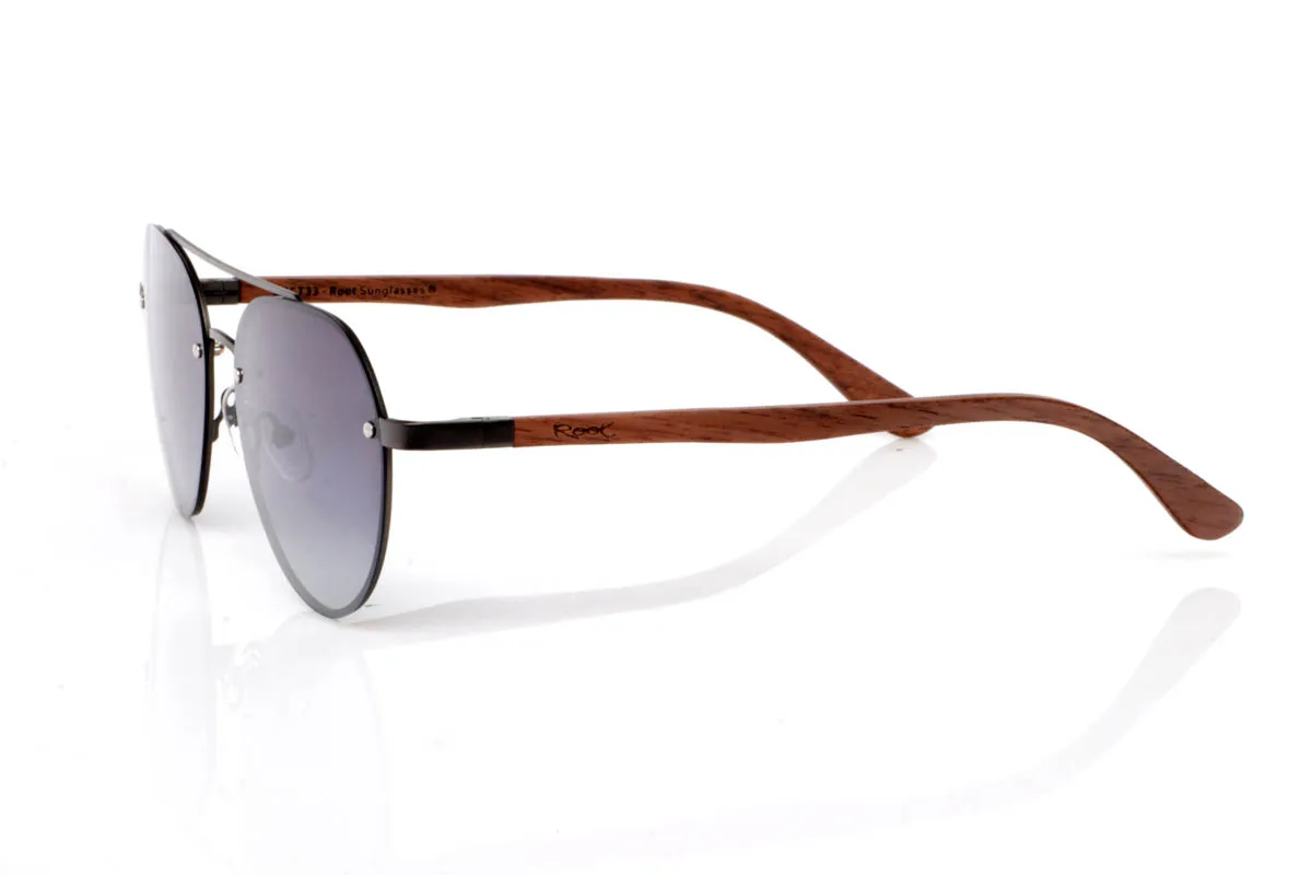 Gafas de Madera Natural de Walnut MISURI ST. Las gafas de madera MISURI ST apuestan por un diseño de inspiración aviador con líneas limpias y estructura metálica fina en tono oscuro, que aporta un aire atemporal y fácil de llevar. Su forma equilibrada estiliza sin exagerar, encajando de forma natural en el día a día.

Las varillas de madera de nogal aportan calidez y contraste, con veta visible y un tacto natural que refuerza la esencia del material. La combinación de metal y madera crea un conjunto ligero, cómodo y con carácter sutil. De esas gafas que acompañan sin imponerse.

Protección completa frente a los rayos UV.

Medidas: 144x51
Calibre: 54 Venta al Por Mayor y Detalle | Root Sunglasses® 