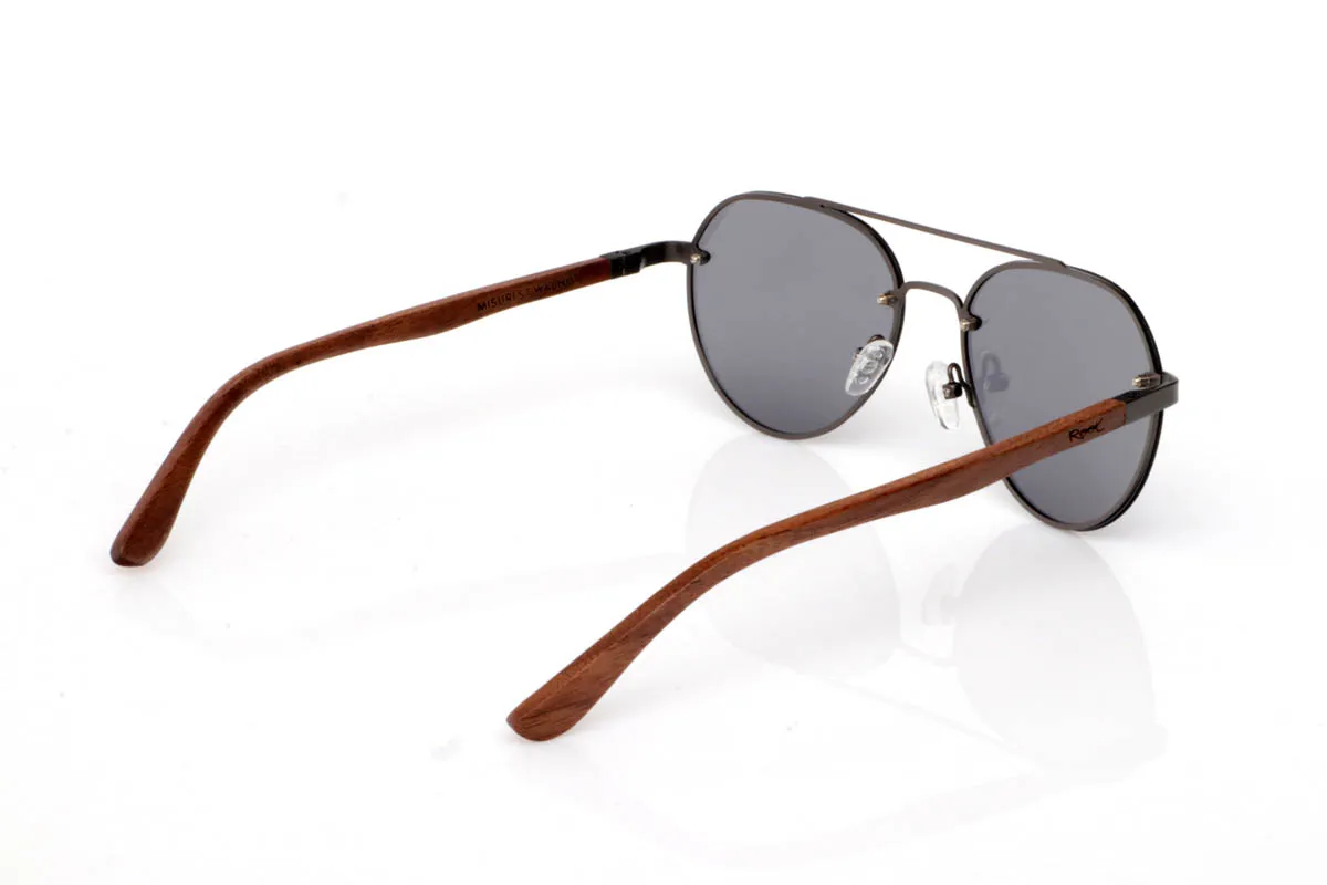 Gafas de Madera Natural de Walnut MISURI ST. Las gafas de madera MISURI ST apuestan por un diseño de inspiración aviador con líneas limpias y estructura metálica fina en tono oscuro, que aporta un aire atemporal y fácil de llevar. Su forma equilibrada estiliza sin exagerar, encajando de forma natural en el día a día.

Las varillas de madera de nogal aportan calidez y contraste, con veta visible y un tacto natural que refuerza la esencia del material. La combinación de metal y madera crea un conjunto ligero, cómodo y con carácter sutil. De esas gafas que acompañan sin imponerse.

Protección completa frente a los rayos UV.

Medidas: 144x51
Calibre: 54 Venta al Por Mayor y Detalle | Root Sunglasses® 